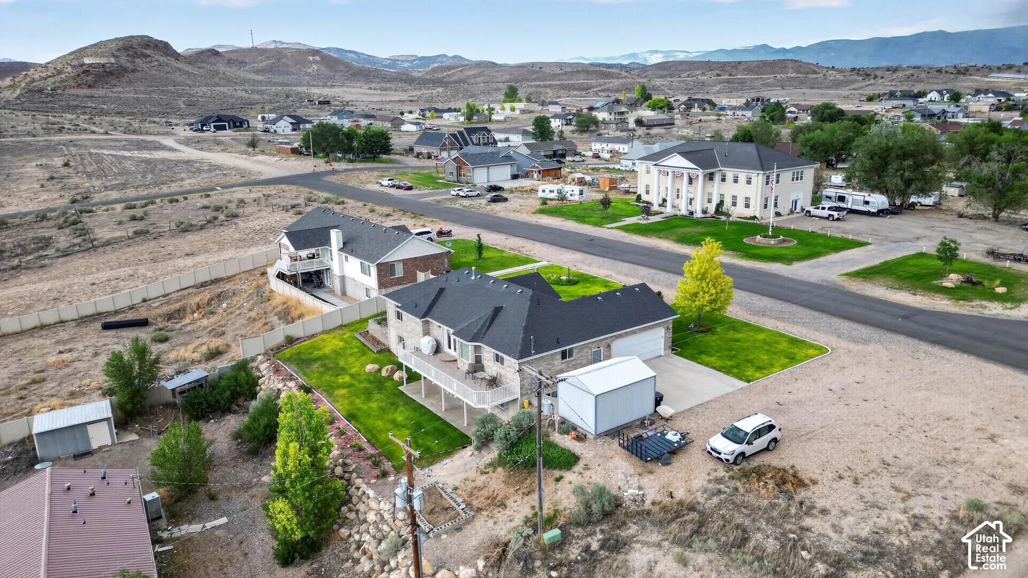 Expansive property featuring a multi-level residence with a tiered deck, attached two-car garage, and a detached metal storage shed