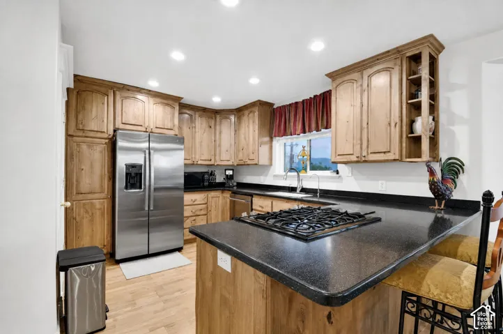 Kitchen featuring wood cabinetry, stainless steel appliances, dark countertops, and recessed lighting