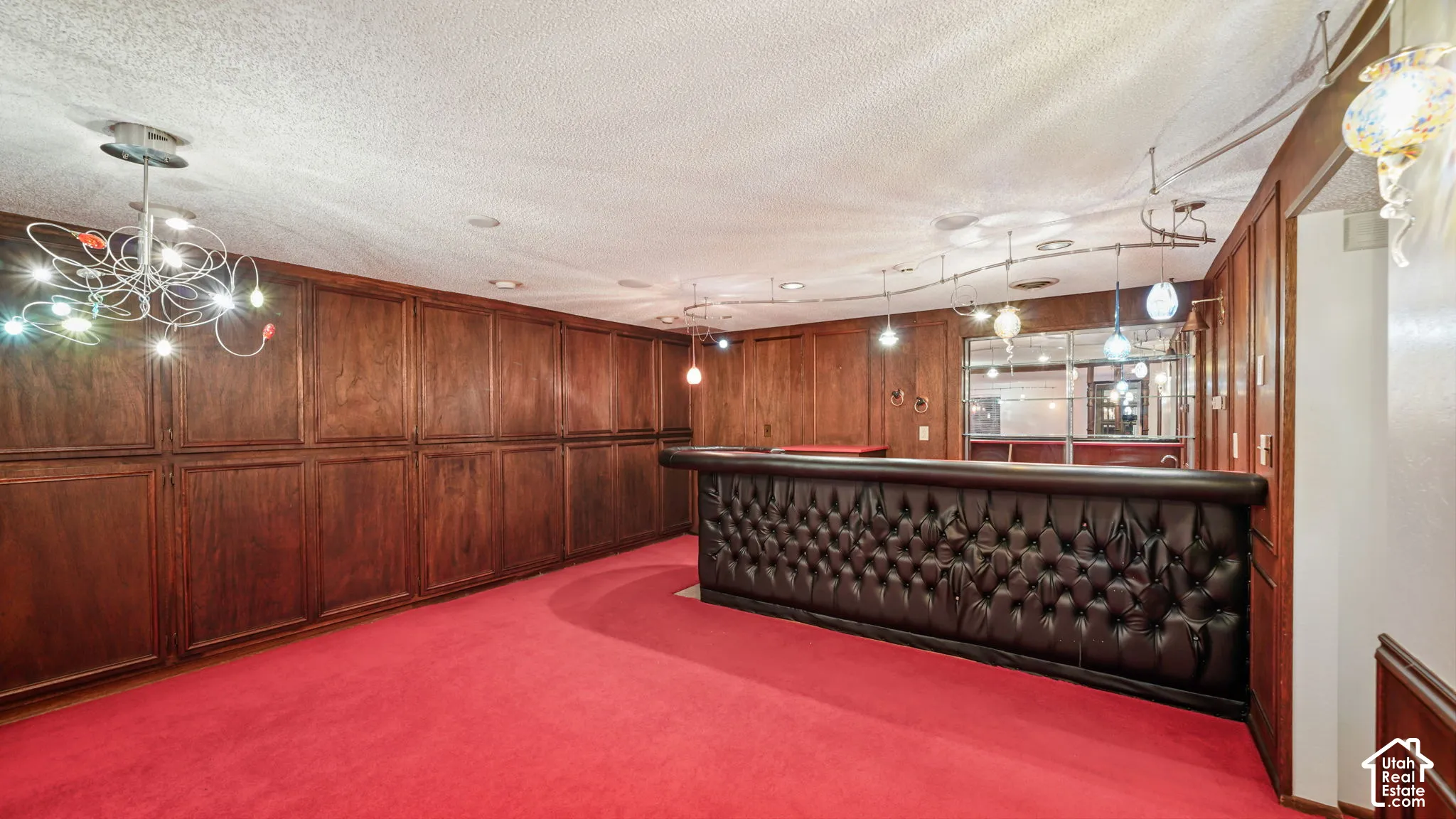 Recreation room featuring extensive wood cupboards for storage and, a built-in bar with tufted upholstery, and red carpeting