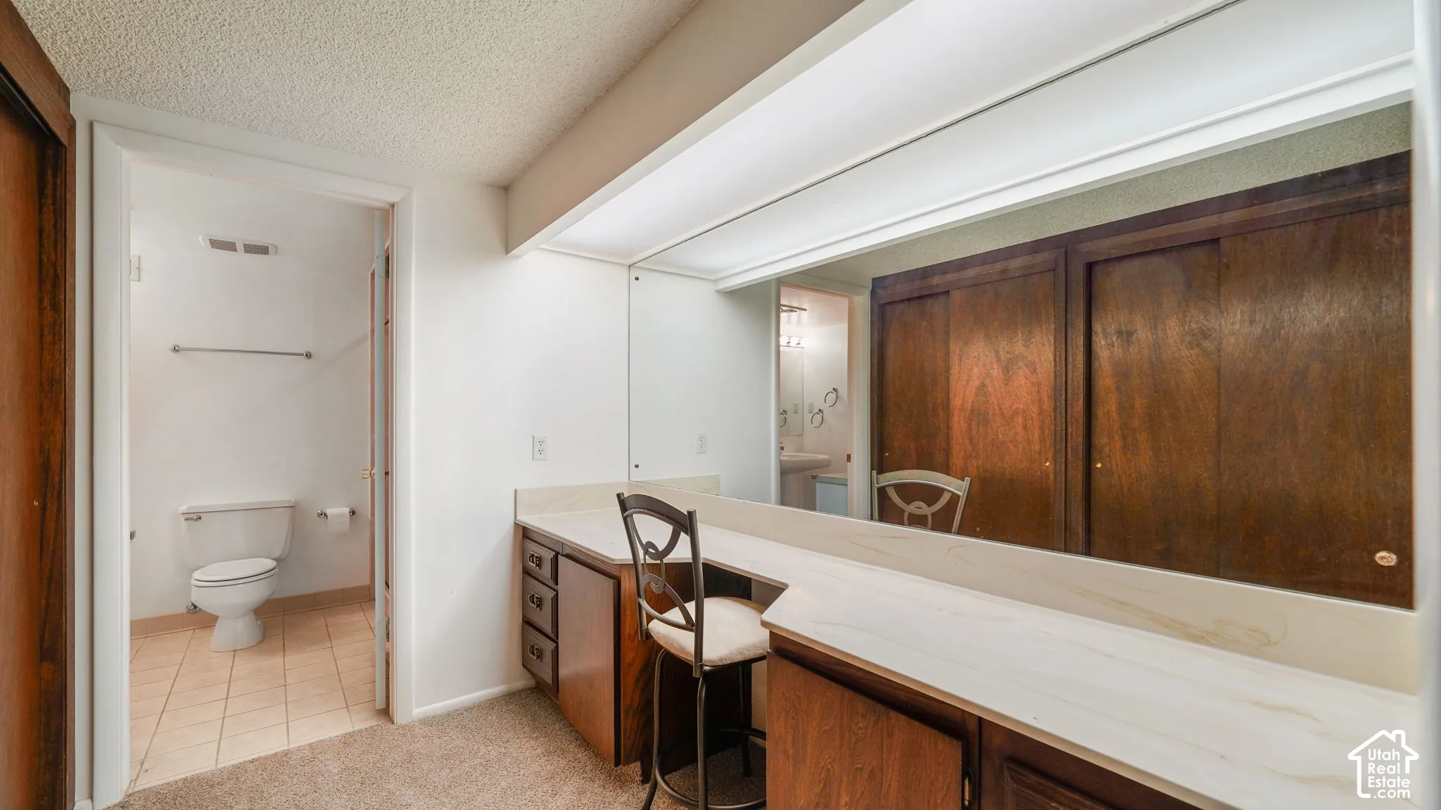 Built-in vanity with a light-toned countertop, integrated mirror, and dark wood-finish cabinetry