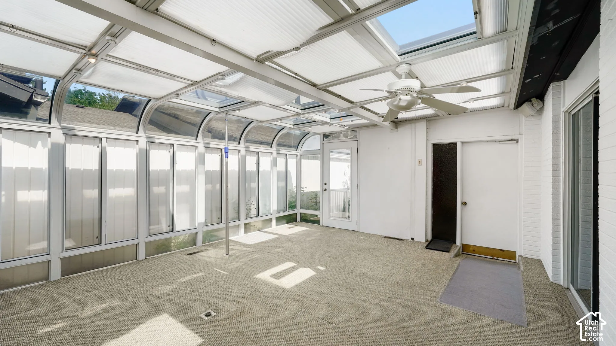 The room has AC and heat. Expansive sunroom featuring a translucent roof, ceiling fan, and light-colored carpeting
