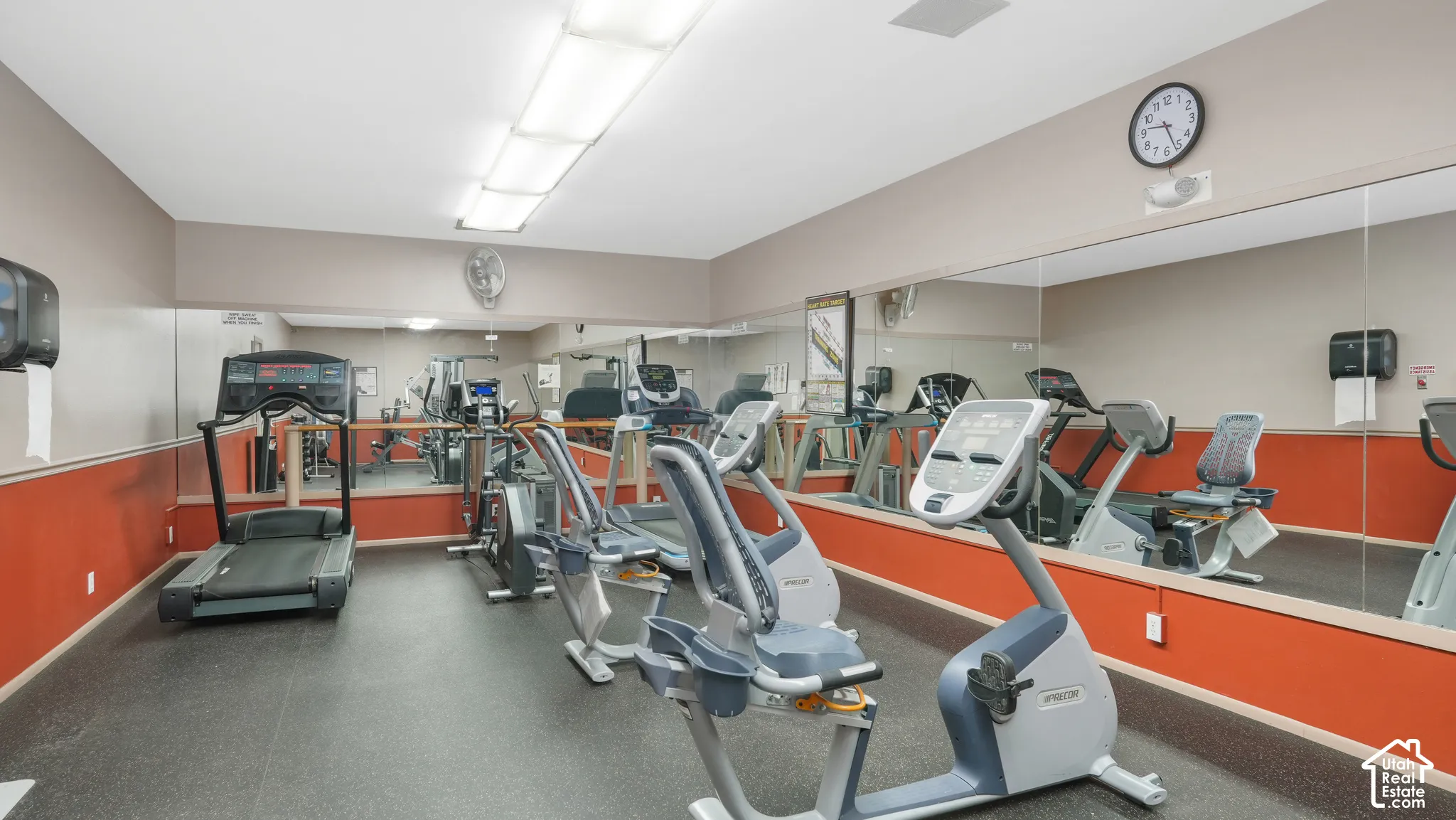 Fitness facility featuring exercise equipment, rubber flooring, mirrored walls, and flush-mounted ceiling lights