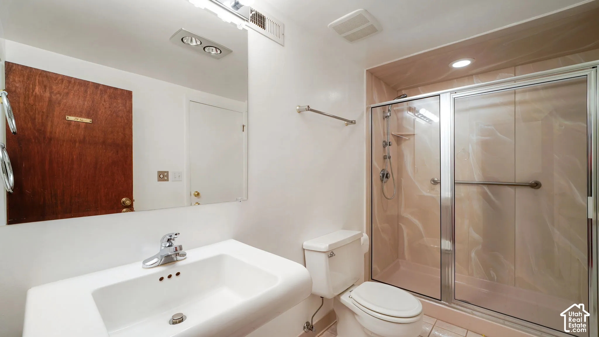 Full bathroom featuring a white pedestal sink, chrome faucet, and a shower enclosure with sliding glass doors