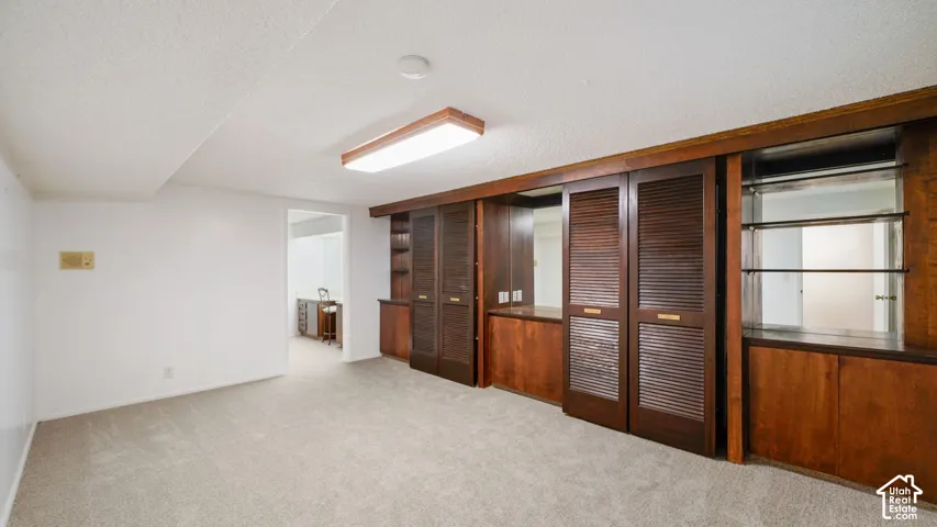 Spacious room featuring extensive built-in Murphy beds with louvered doors, integrated shelving, and illuminated glass display shelves