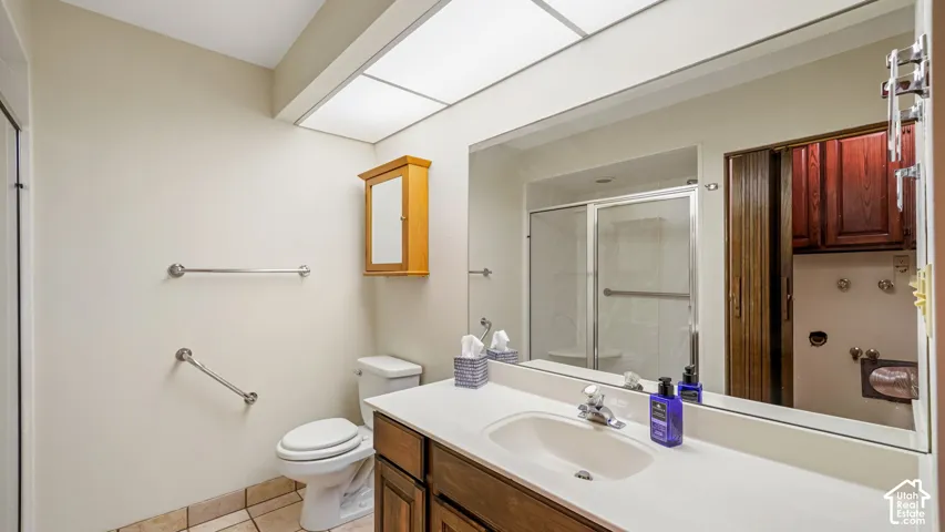 Bathroom featuring a white vanity with integrated sink, wood-finish cabinetry, a large wall-mounted mirror, and a fluorescent ceiling light