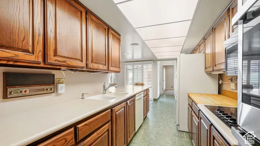 Galley kitchen featuring wood cabinetry, solid surface countertops, and integrated appliances