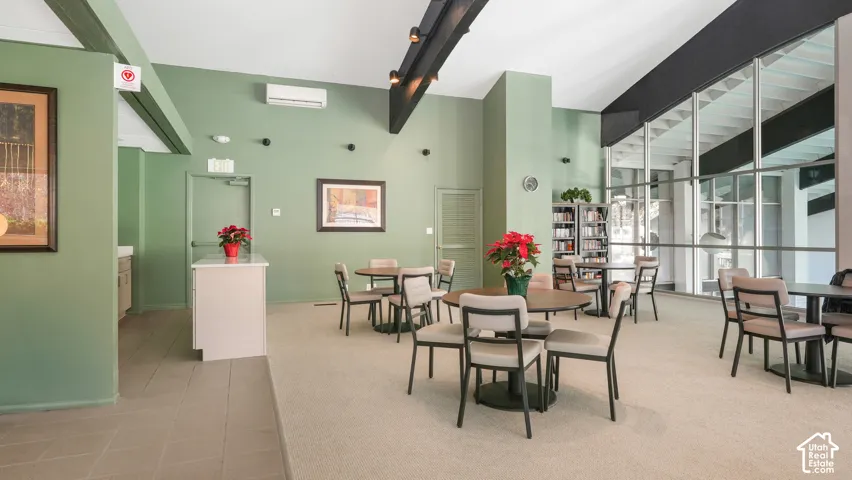 Spacious common area featuring vaulted ceilings with exposed beams, large format windows, built-in shelving, and a tiled serving counter