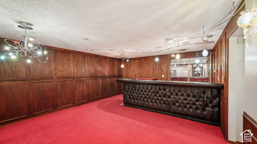 Recreation room featuring extensive wood cupboards for storage and, a built-in bar with tufted upholstery, and red carpeting