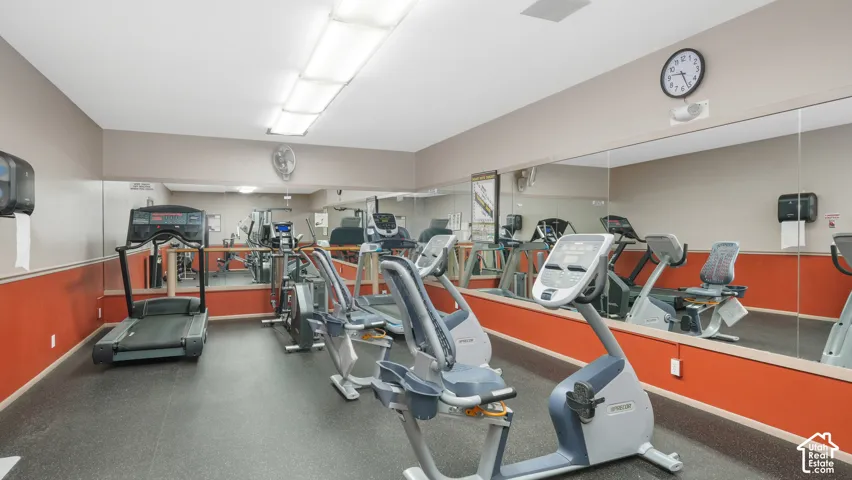 Fitness facility featuring exercise equipment, rubber flooring, mirrored walls, and flush-mounted ceiling lights