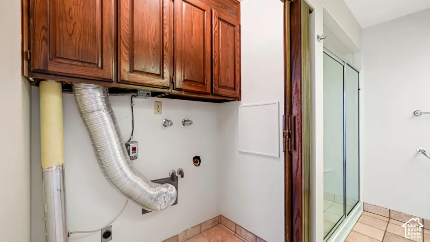 Laundry area with wood-finish cabinetry, tile flooring, and dedicated appliance hookups