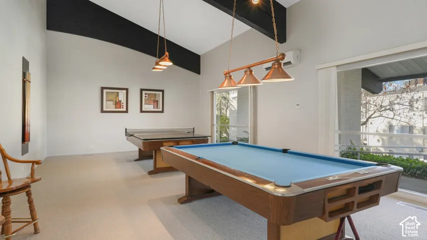 Vaulted ceiling room with exposed dark beams and light carpeting