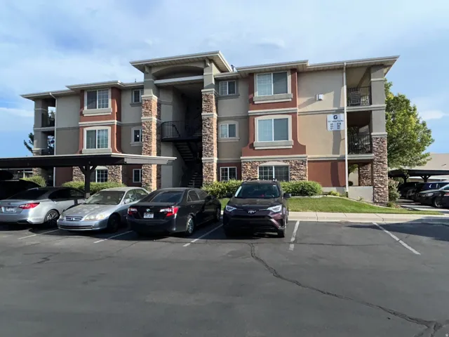 Multi-story residential building featuring stone veneer accents, multiple balconies, and exterior staircases