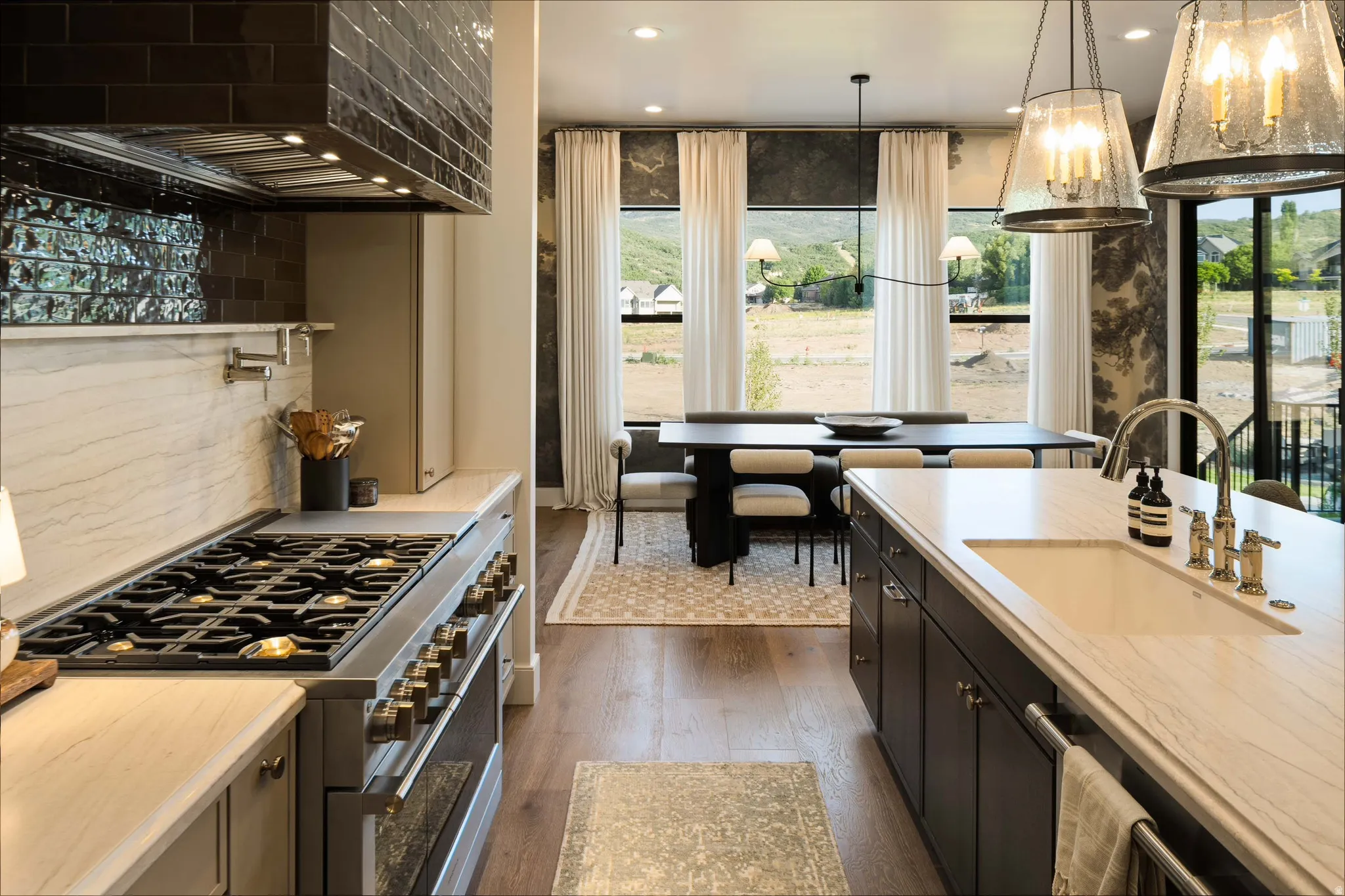 Gourmet kitchen and dining area featuring a professional-grade range, a large center island with an integrated sink, dark wood-finish cabinetry, and wood-finish flooring