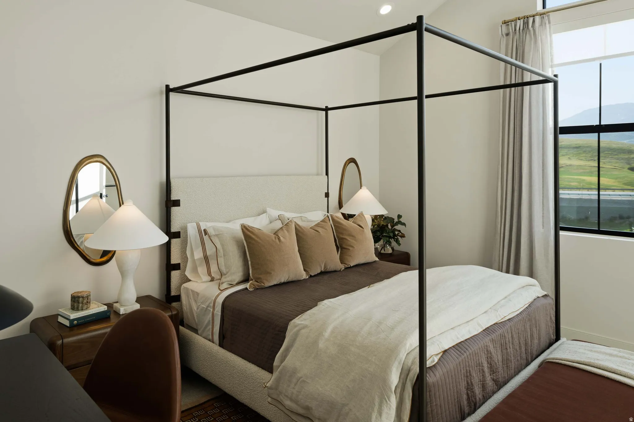 Bedroom featuring a black metal four-poster bed frame, upholstered headboard, and recessed lighting