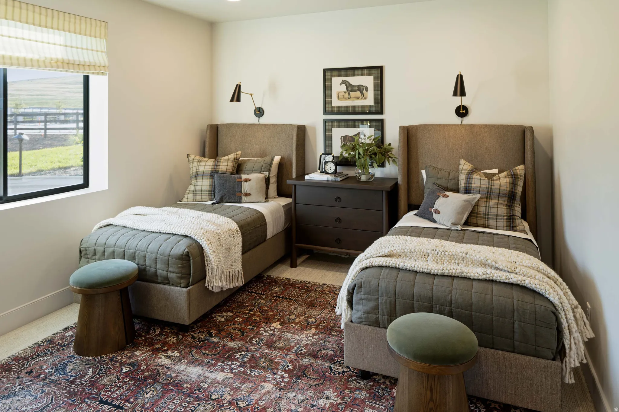 Room featuring two wingback upholstered beds, a shared three-drawer dark wood nightstand, and dual wall-mounted sconces