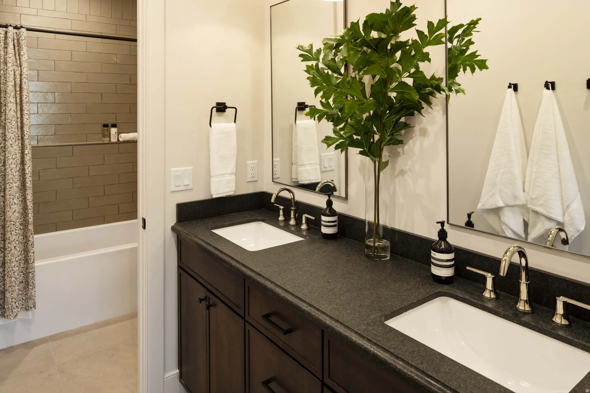 Dual vanity featuring dark cabinetry, speckled countertops, and undermount sinks with brushed nickel fixtures