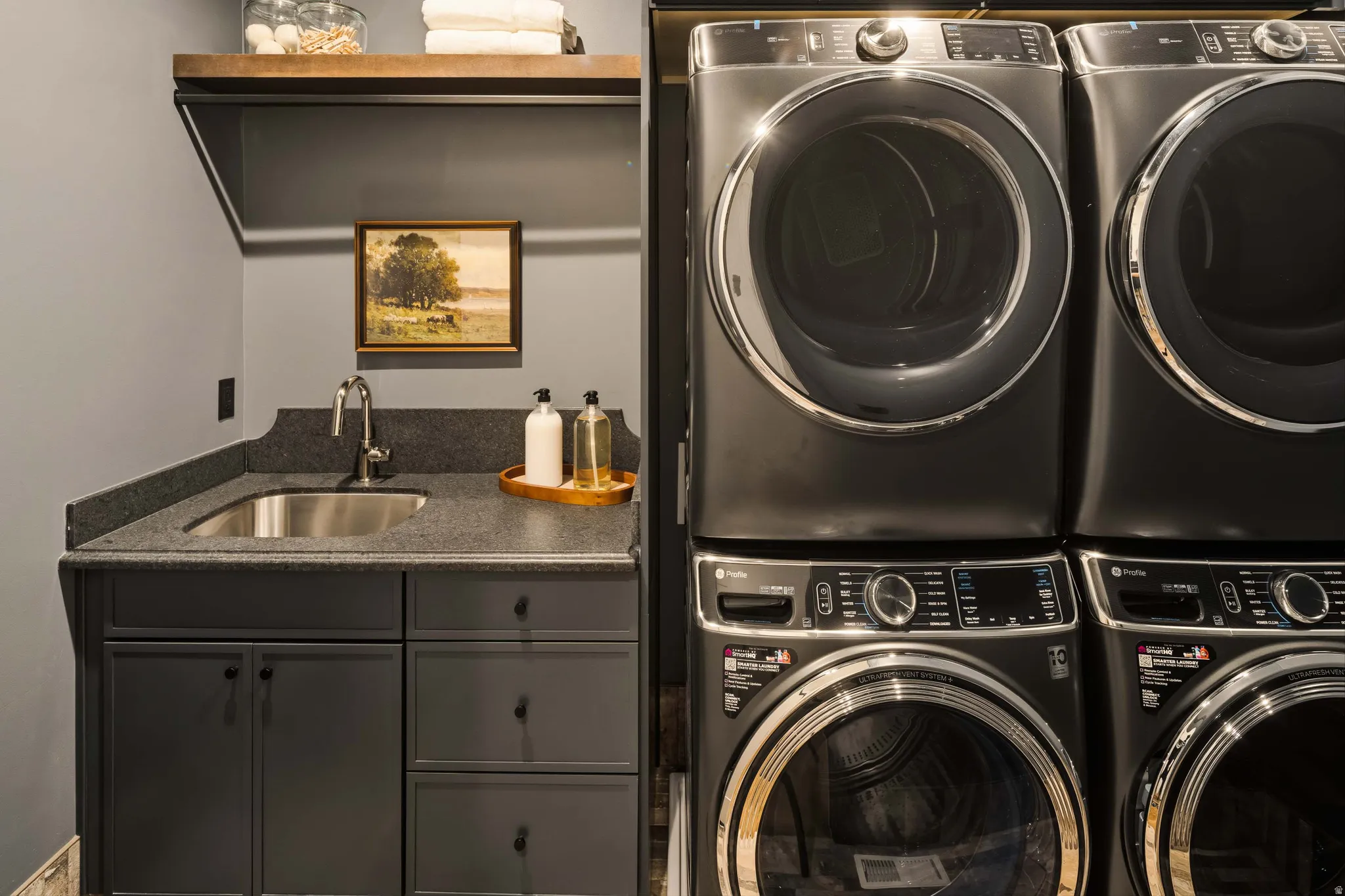 Laundry area featuring a built-in utility sink, dark cabinetry, and a dark stone-finish countertop