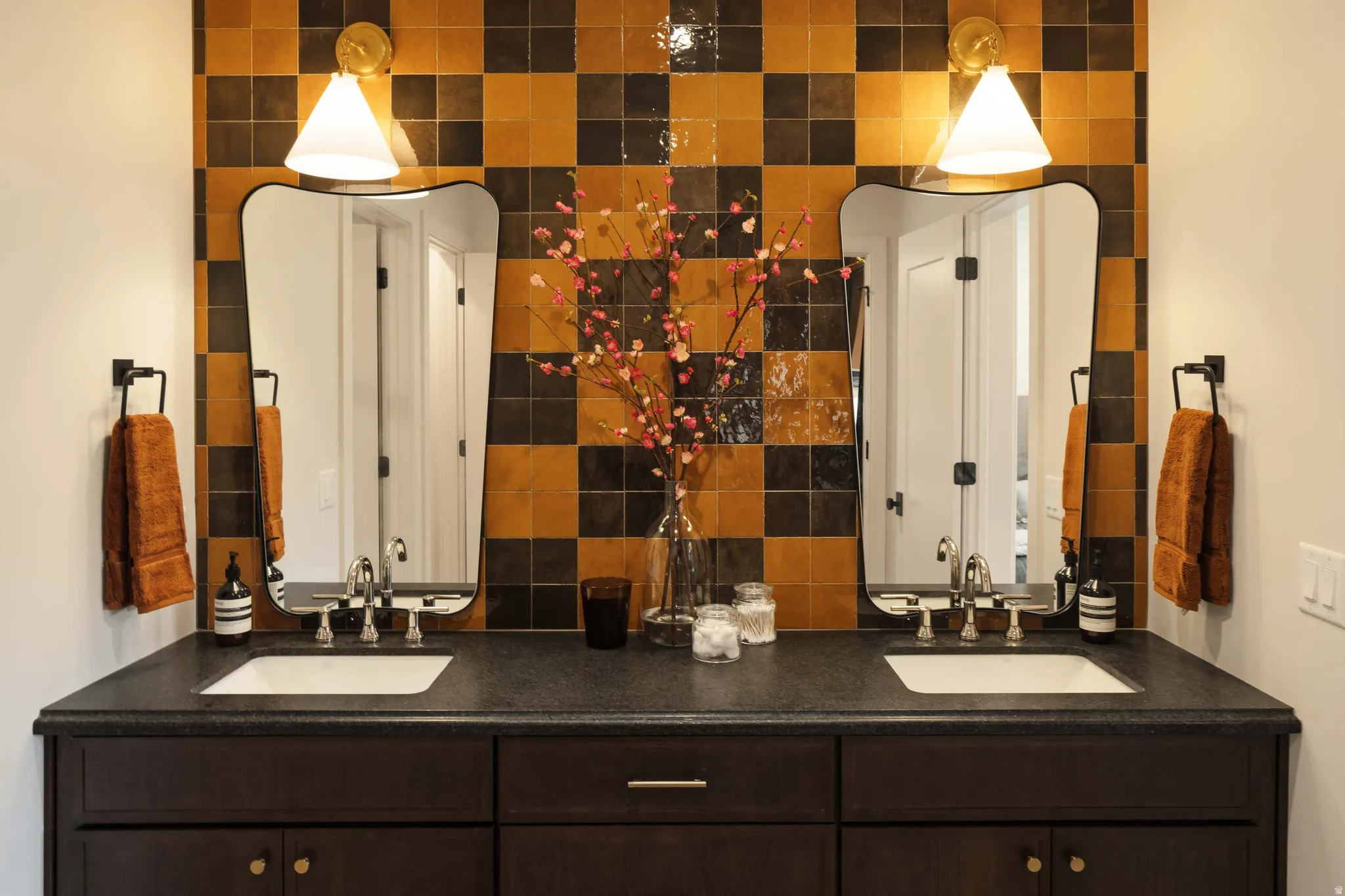 Dual vanity with a dark wood-finish cabinet, dark countertop, and integrated sinks