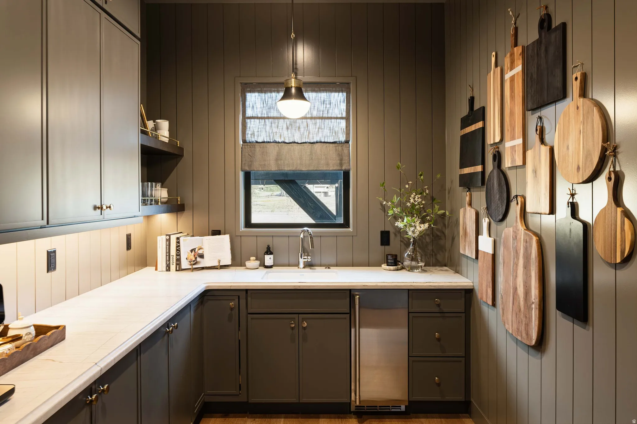 Wet bar featuring panel-style cabinetry, a built-in beverage refrigerator, a single basin sink with a gooseneck faucet, light-toned countertops, and vertical plank wall paneling
