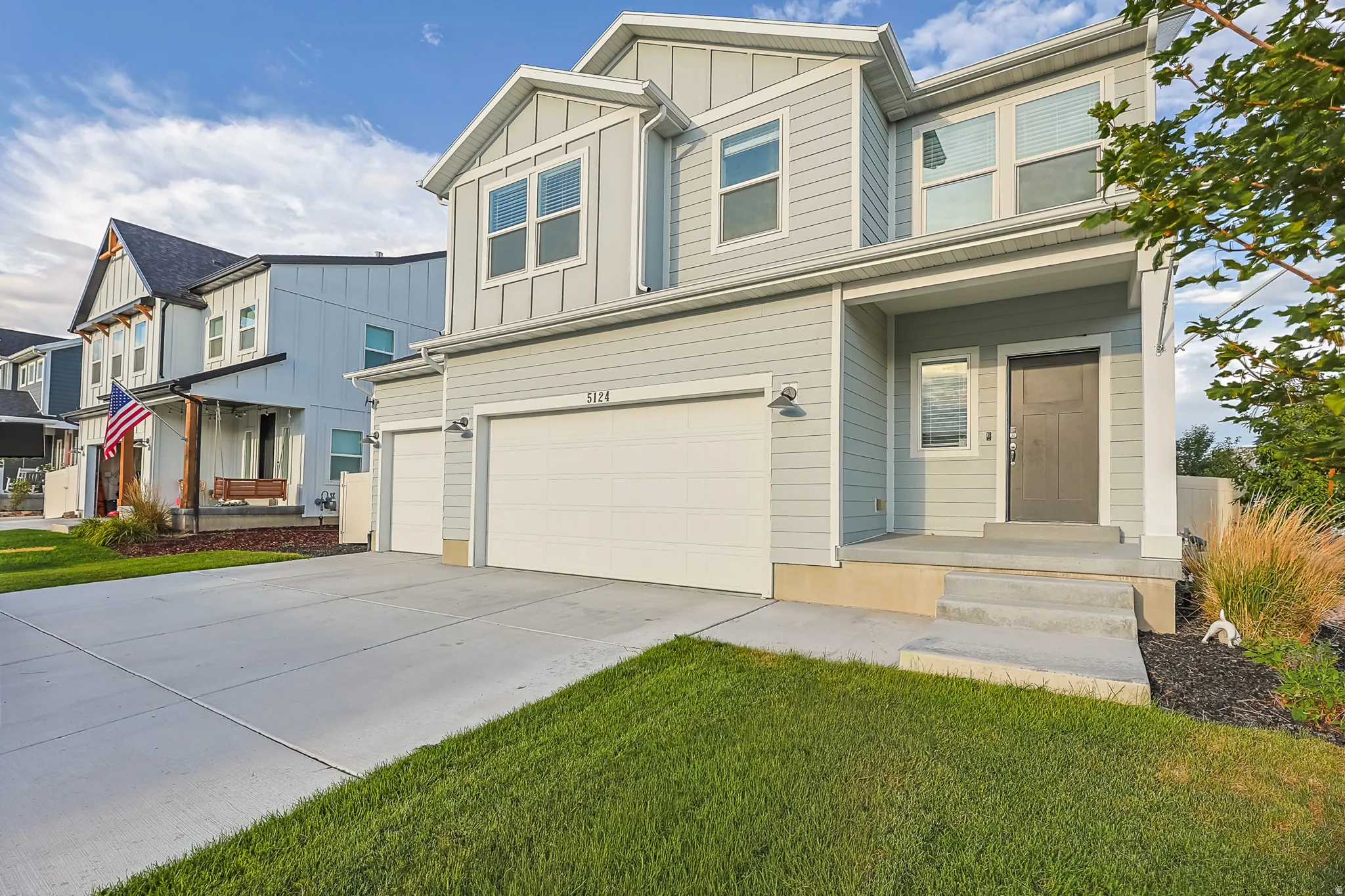 Two-story residence featuring light gray siding with white trim, 3 car garage