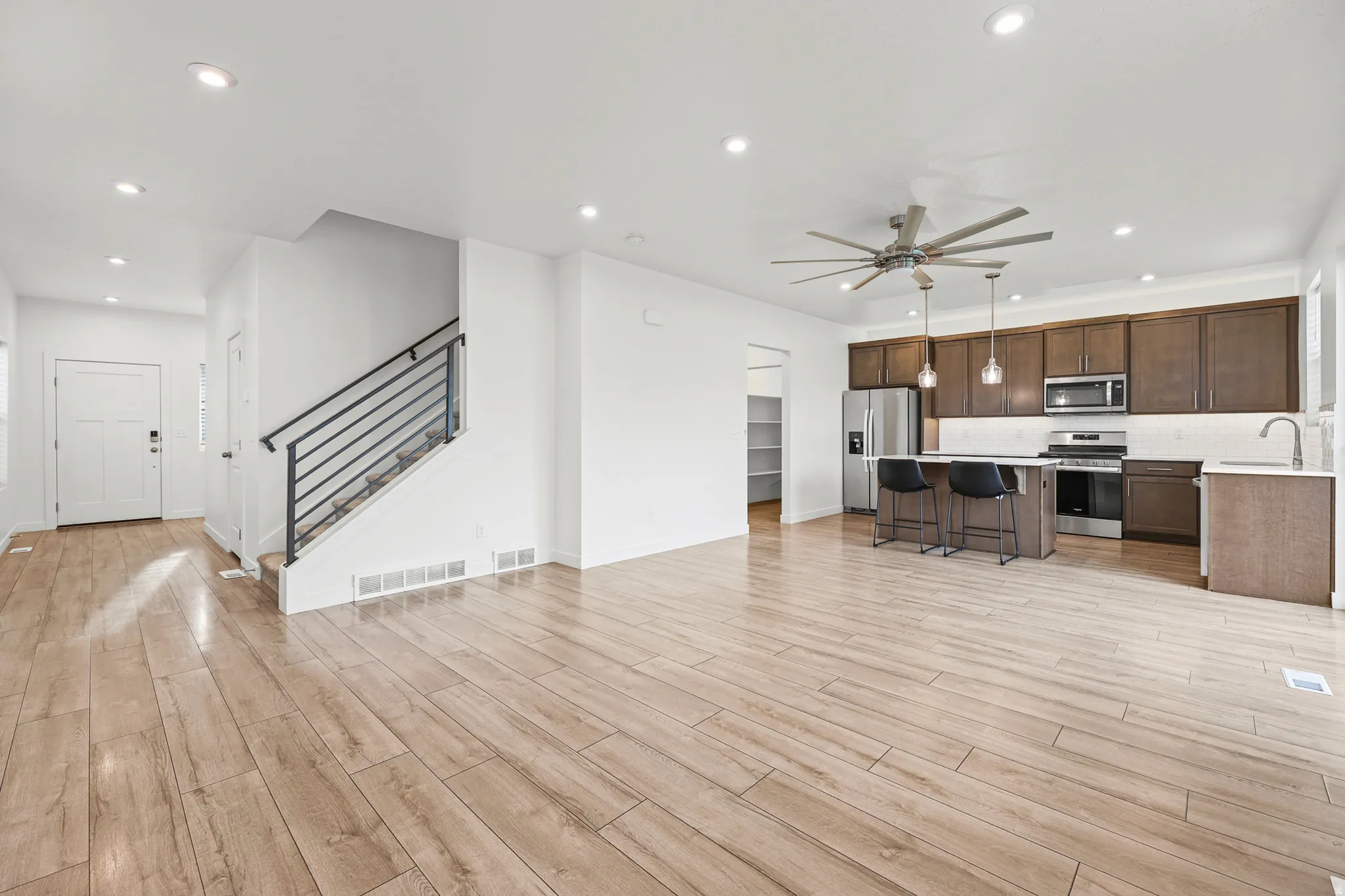 Open-concept living area featuring wood-finish flooring, recessed lighting, and a modern kitchen
