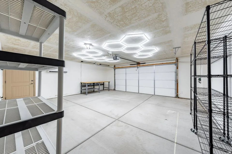 Garage space featuring contemporary hexagonal ceiling lighting, a workbench, and robust storage shelving