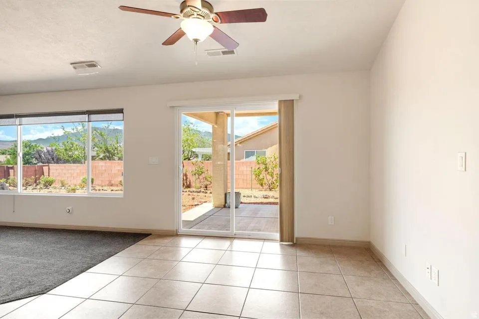Spacious room featuring large format tile flooring and a ceiling fan