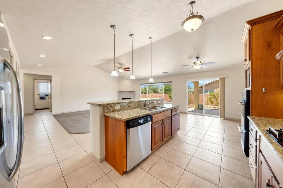 Open-concept kitchen featuring an island with double sink, stainless steel dishwasher, and pendant lighting