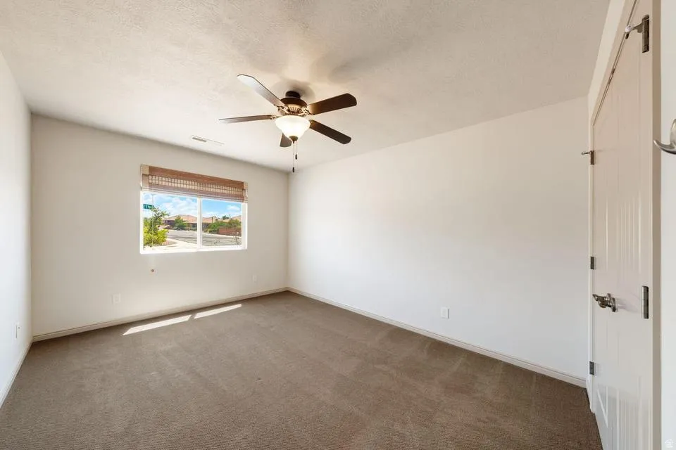 Room featuring neutral-toned carpet flooring, white walls, and a window with a woven shade