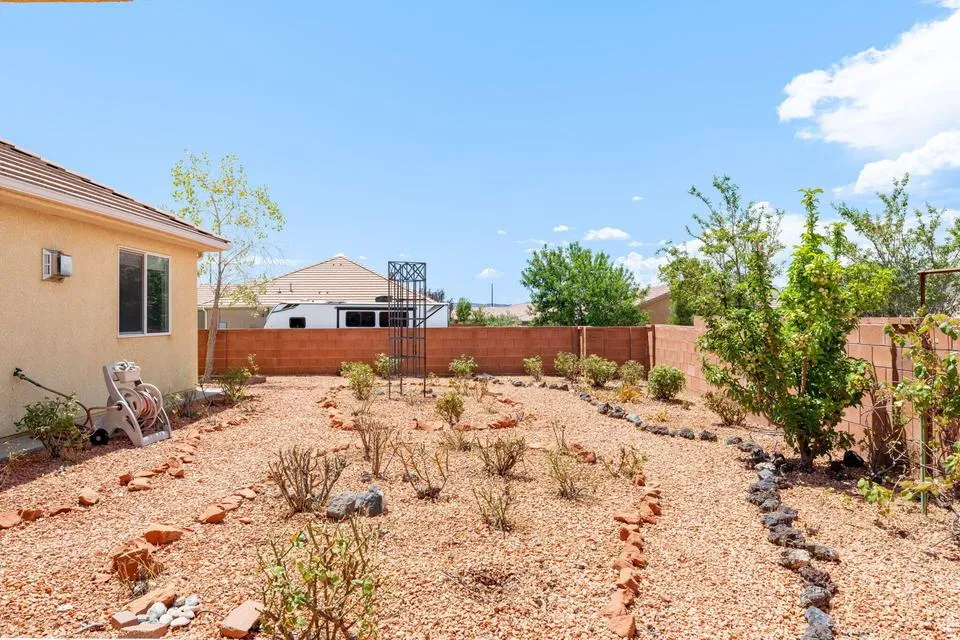 Expansive backyard featuring a red brick perimeter wall, gravel landscaping, and various plantings