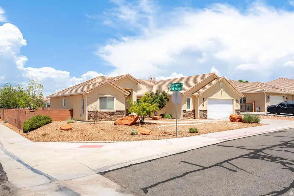 Corner lot residence featuring a stucco exterior with stone accents, a single-car garage, and a tile roof