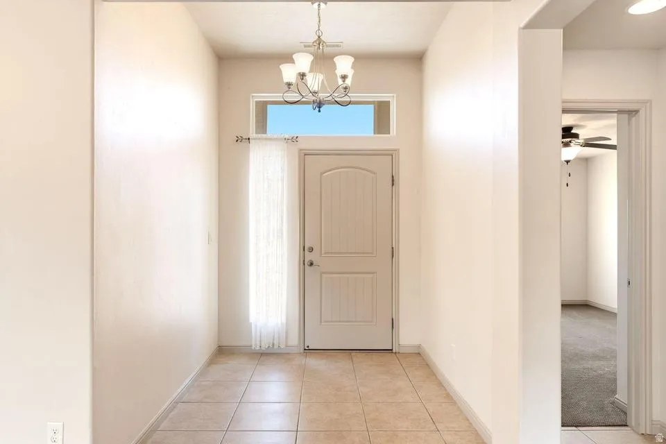 Entryway featuring a decorative chandelier, transom window, and tile flooring