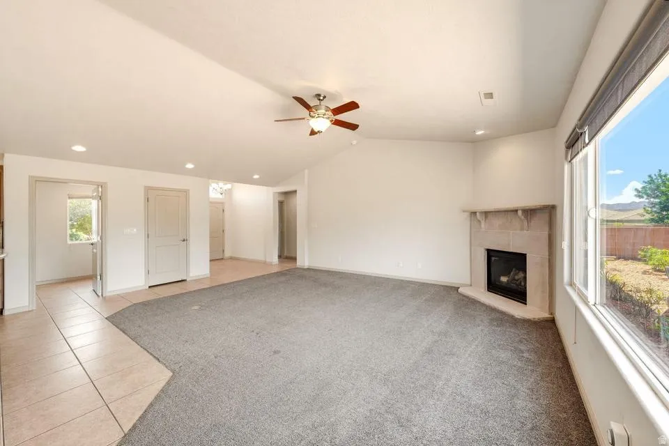 Spacious living area featuring a corner fireplace with stone surround, recessed lighting, and a ceiling fan