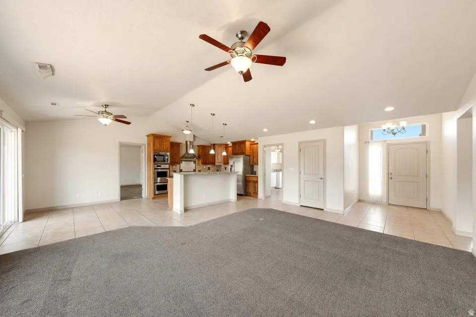 Open-concept living area featuring a kitchen with wood cabinetry, stainless steel appliances, and a breakfast bar