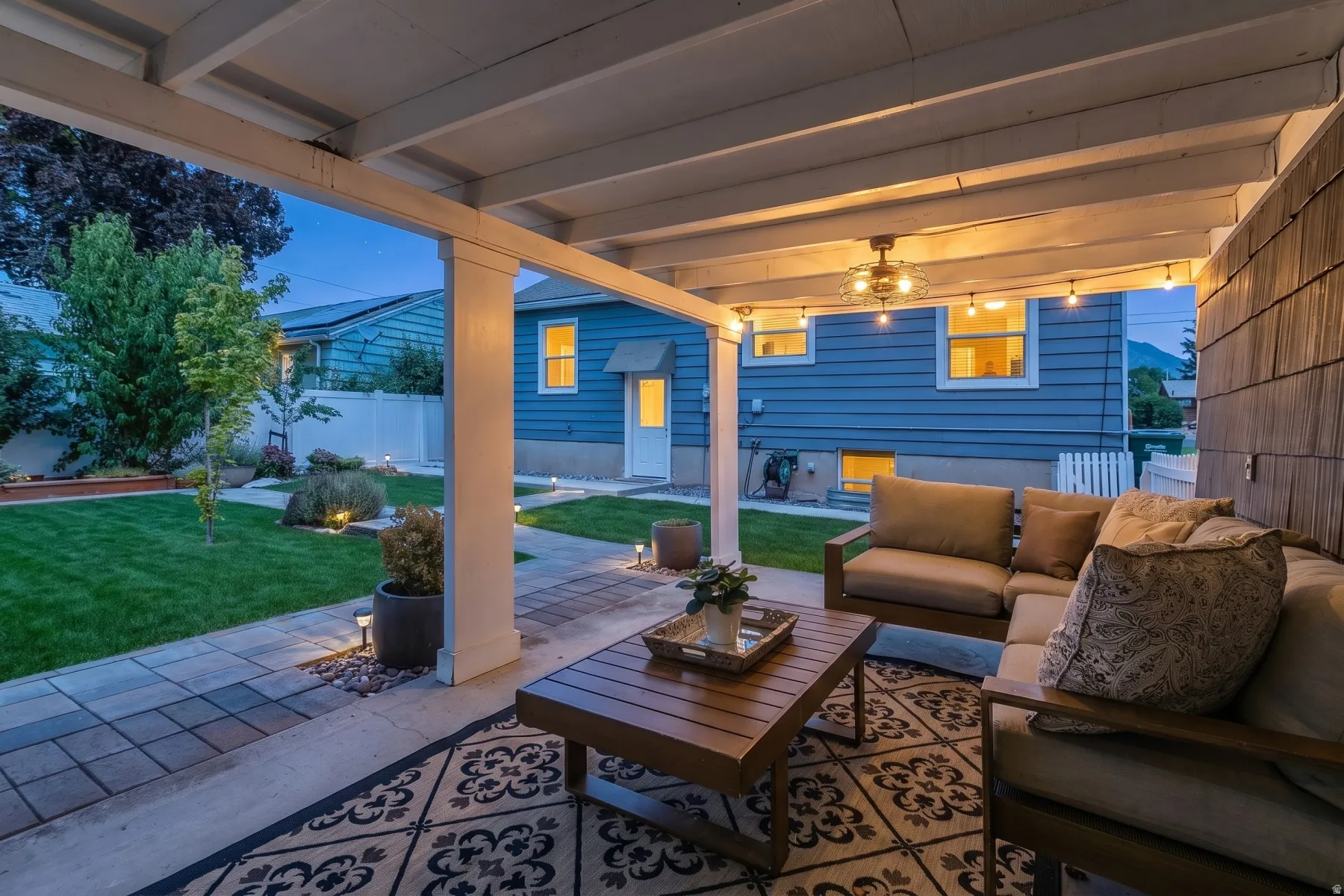 Covered patio featuring string lighting, a ceiling fan, and a wood-slat accent wall
