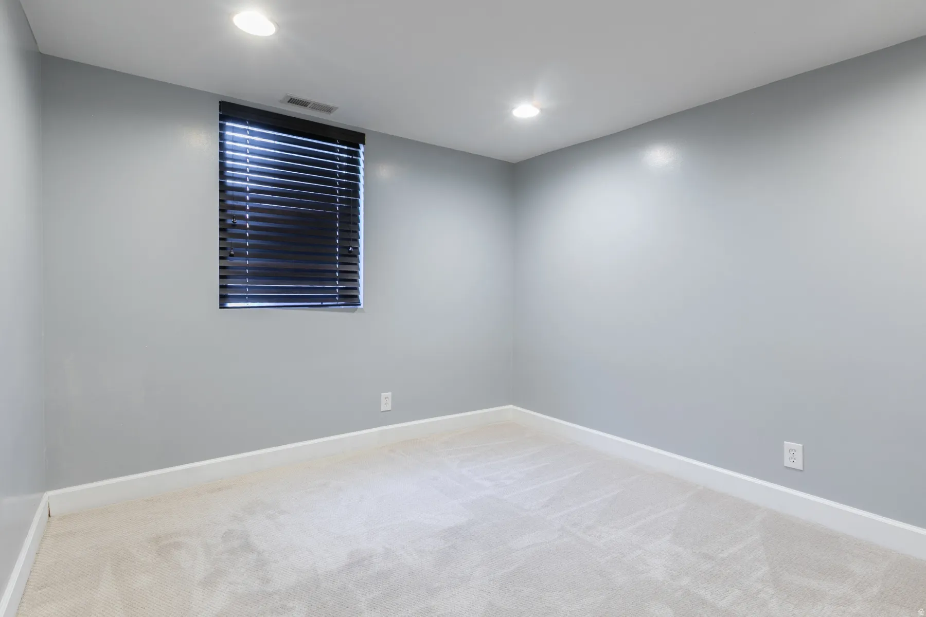 Room featuring light gray walls, recessed lighting, and a window with dark blinds