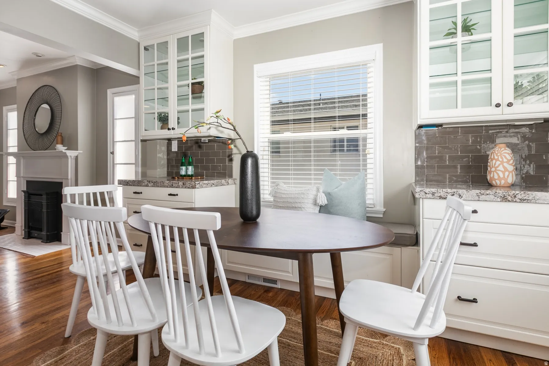 Built-in window bench seating complemented by white shaker-style cabinetry with glass-front upper cabinets