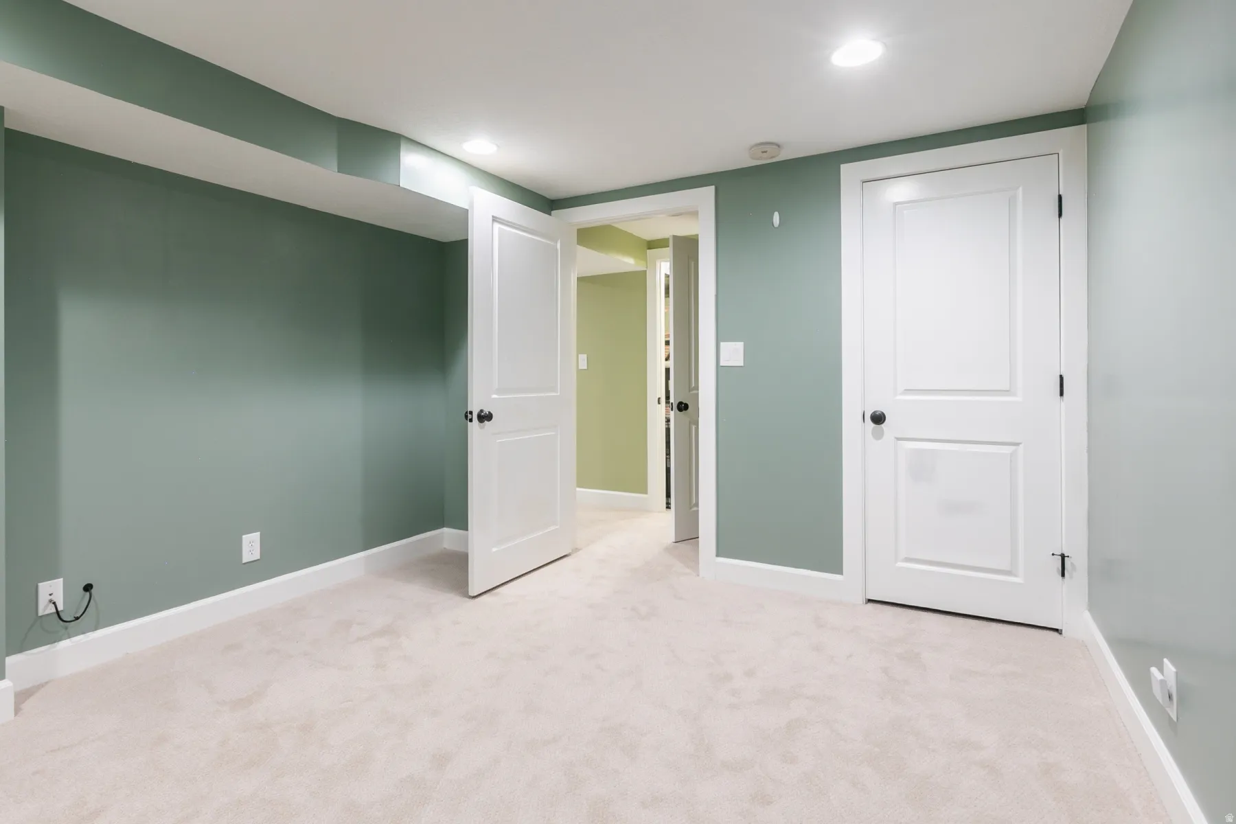 Spacious room featuring plush carpeting, recessed lighting, and crisp white trimwork