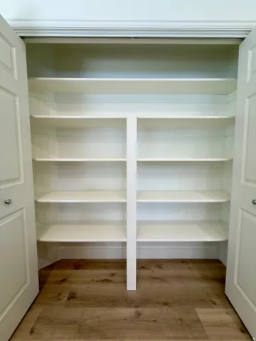 Built-in pantry shelving featuring white painted wood, providing multiple tiers of storage