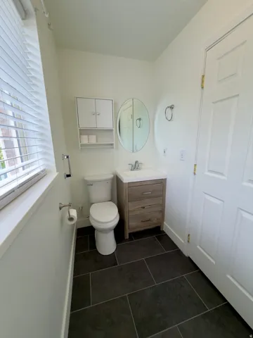Half bathroom featuring dark floor tiles, and a wood-finish vanity with an integrated sink