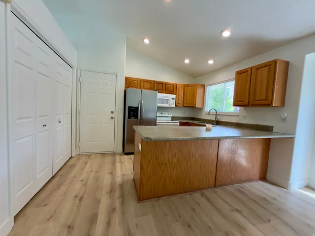 Kitchen featuring LVP flooring, vaulted ceiling, large pantry and recessed lighting