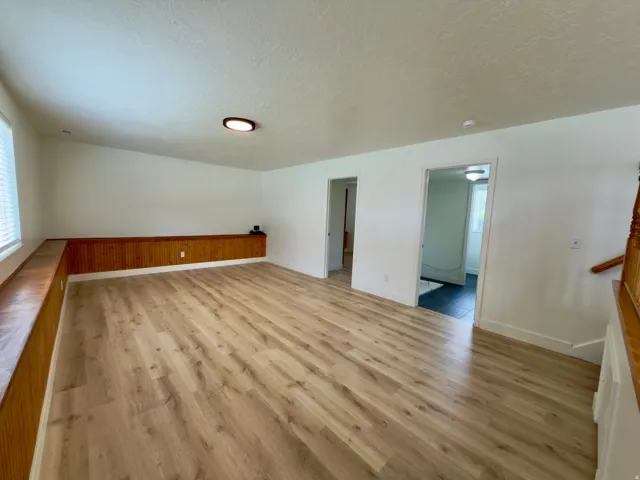 Spacious family room featuring new LVP flooring, and a built-in wood-paneled bench. Laundry & bedroom just off family room.