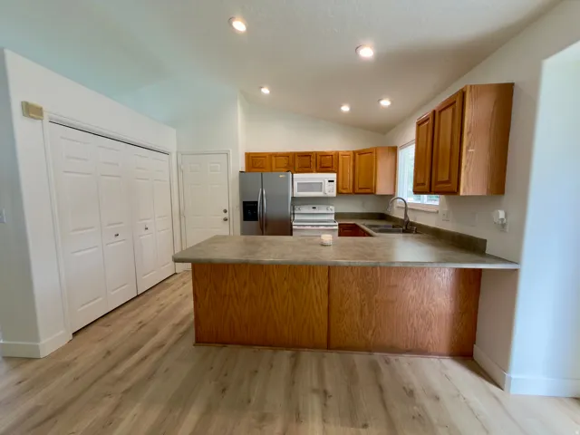 Kitchen featuring wood-finish cabinetry, stainless steel refrigerator, large pantry and a built-in microwave