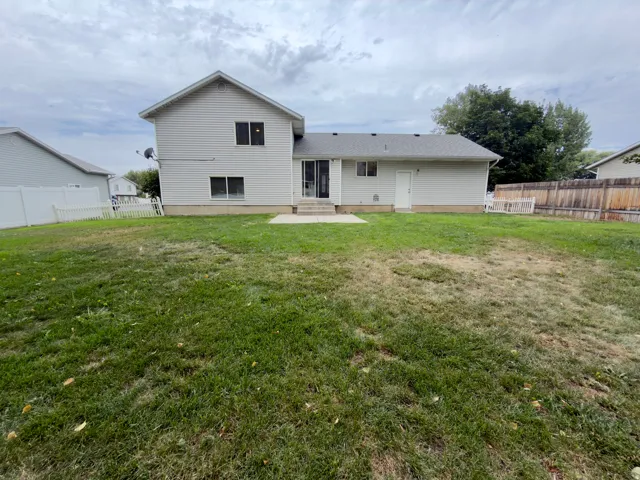 Expansive backyard featuring a concrete patio, white vinyl fencing, and wood fencing