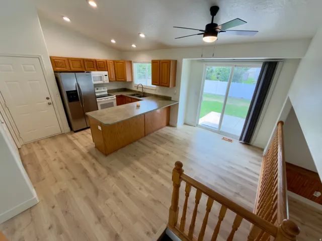 Open-concept kitchen and dining areas featuring LVP flooring, vaulted ceilings with recessed lighting, and a ceiling fan