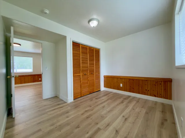Bedroom featuring LVP flooring, wood-paneled wainscoting with a display shelf, and a double-door closet