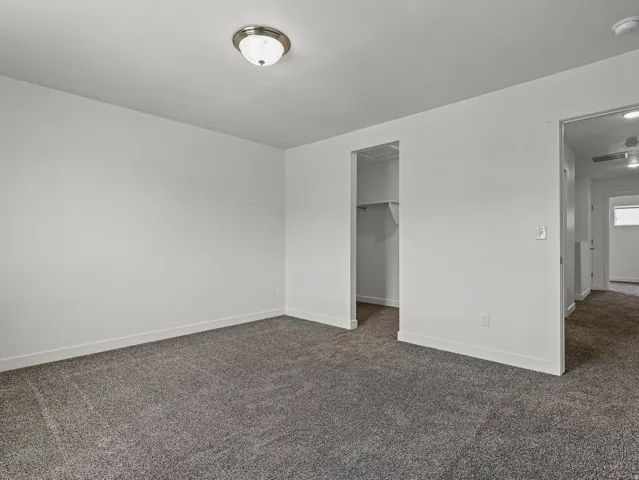 Spacious room featuring neutral carpeting, white walls, and a ceiling-mounted light fixture