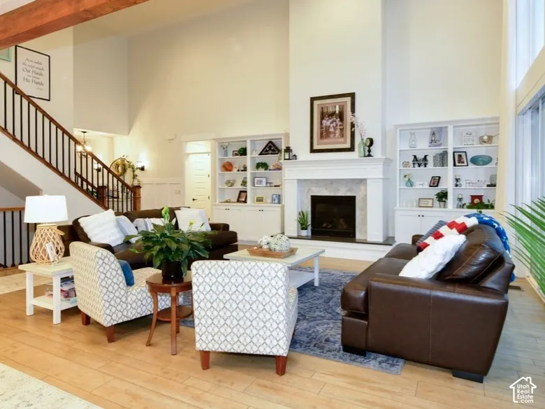 Spacious living area featuring a two-story ceiling, wood-finish flooring, and a prominent fireplace with a substantial mantel