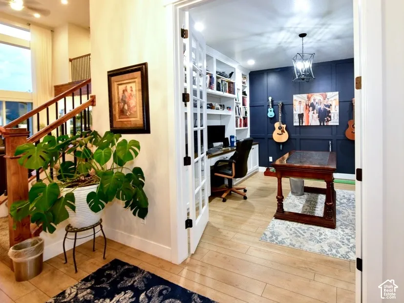 Office space featuring French doors, built-in shelving, wood-finish flooring, and a decorative paneled accent wall