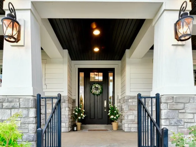 Inviting covered porch with stone base pillars and exterior wall sconces